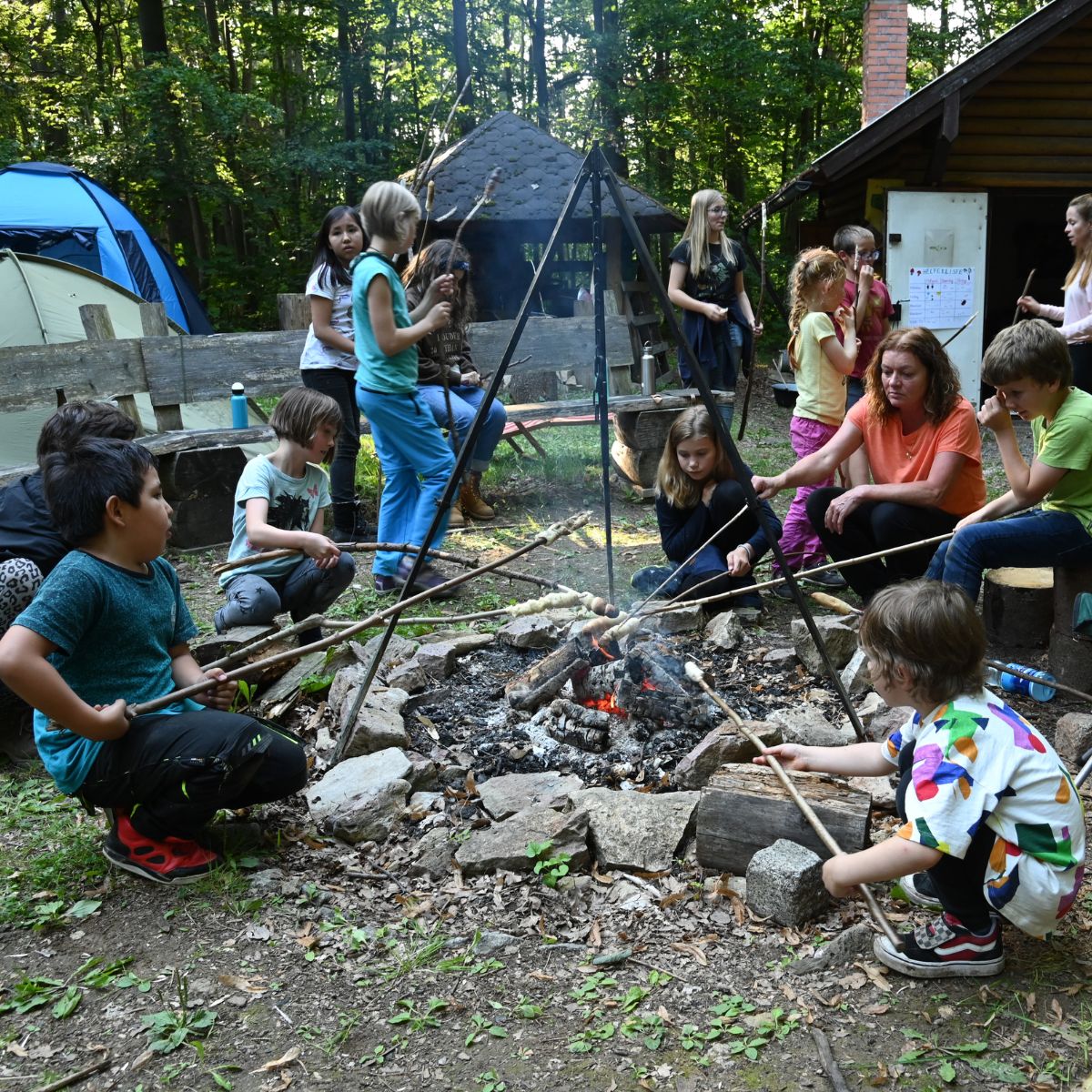 Kinder grillen Stockbrot am Lagerfeuer im Wald.