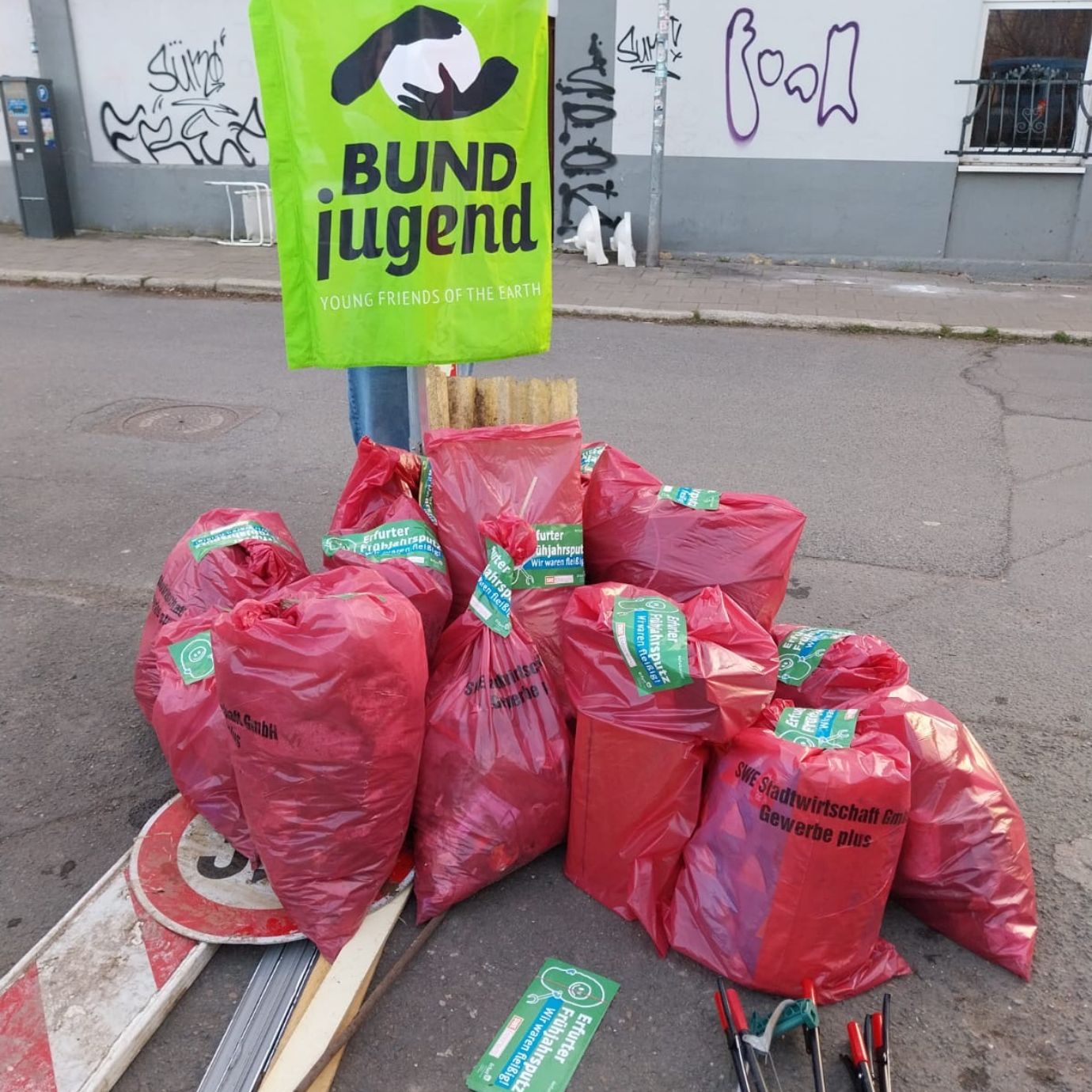 Rote Müllsäcke mit Banner von BUNDjugend auf der Straße.