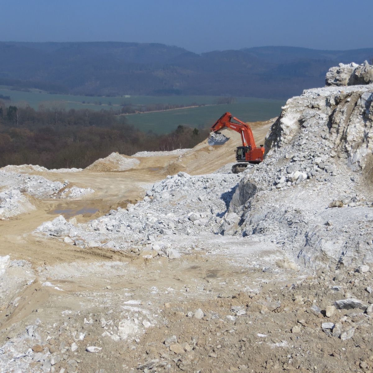 Bagger in einem Steinbruch am Hügel