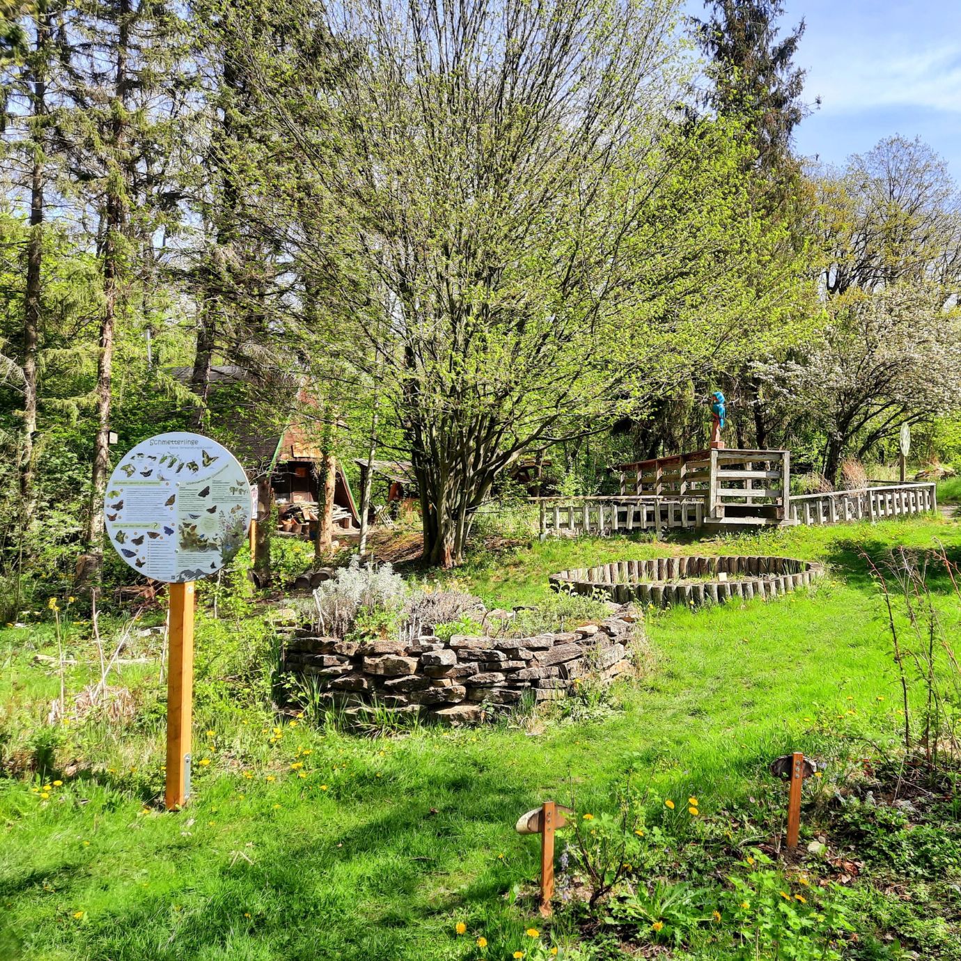 Fuchsfarm Erfurt Grüner Garten mit Infotafel und Steinumrandung.